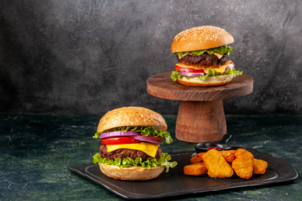 delicious-sandwiches-fries-chicken-nuggets-black-cutting-board-fries-pepper-dark-mix-colored-blurred-surface