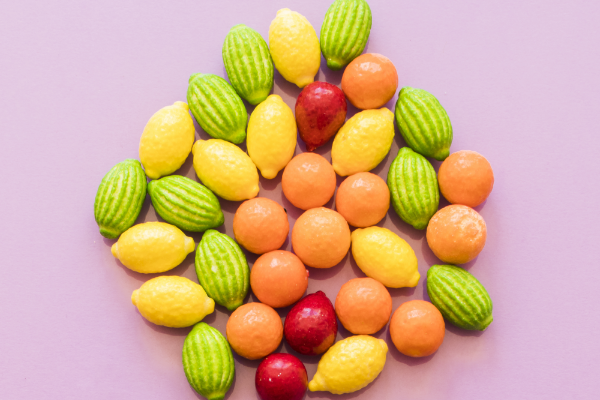 overhead-view-colorful-fruit-shape-candies-pink-background